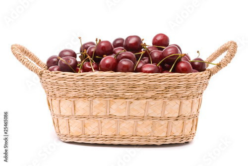 Red cherries in wooden basket isolated on white