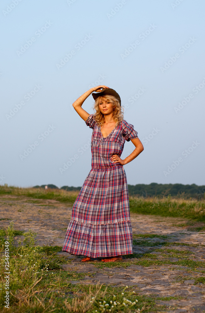 Beautiful blond young woman in a cowboy hat and dress Beautiful blond young woman in a cowboy hat and dress