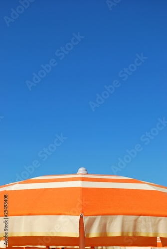 Obraz na płótnie Orange striped beach umbrella on blue sky, Rimini, Italy w salonie