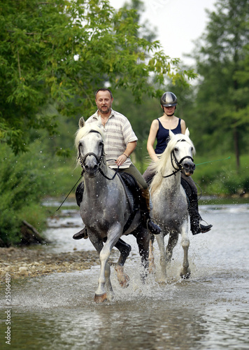 Ein Mann und eine Frau reiten durch eine Fluss