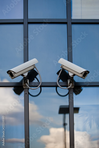 Two security cameras attached on business building with reflecti