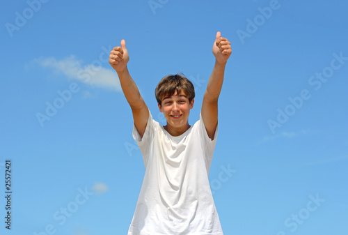 happy teenager with thumbs up on the blue sky background