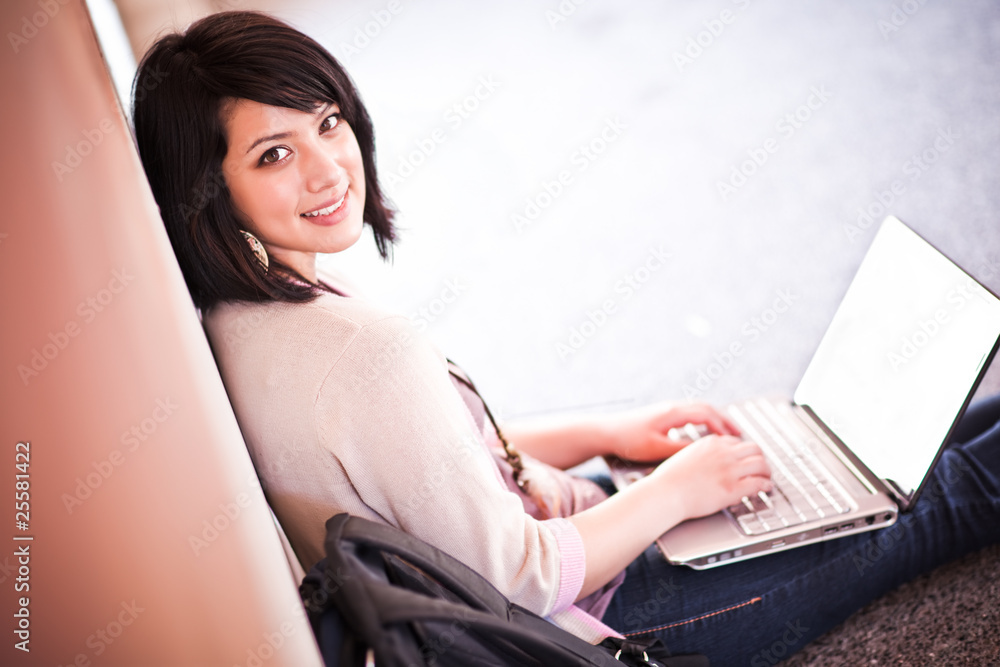 Naklejka premium Mixed race college student with laptop
