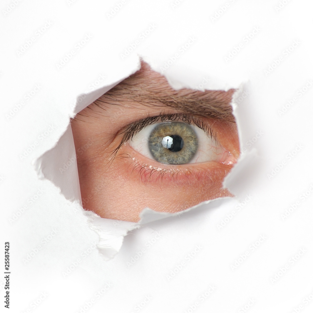 Fototapeta premium Eye looking through a hole in paper
