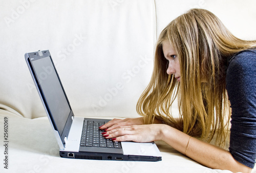 Young girl working with a laptop on the couch