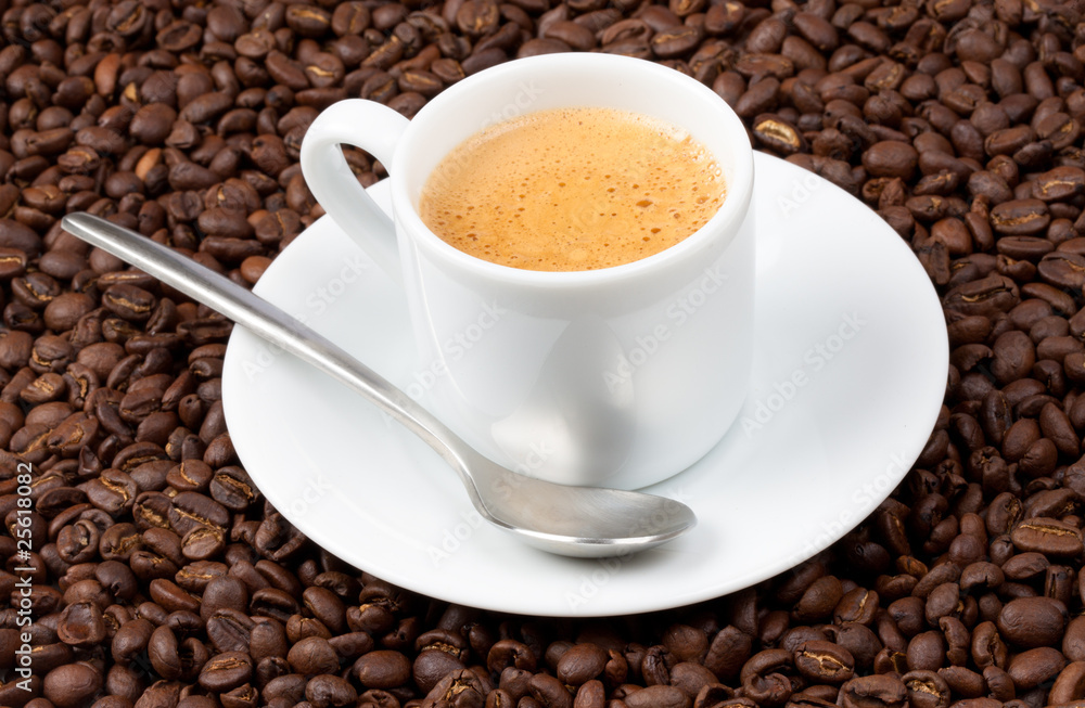 White espresso cup full of coffee sat on coffee beans White espresso cup full of coffee sat on coffee beans