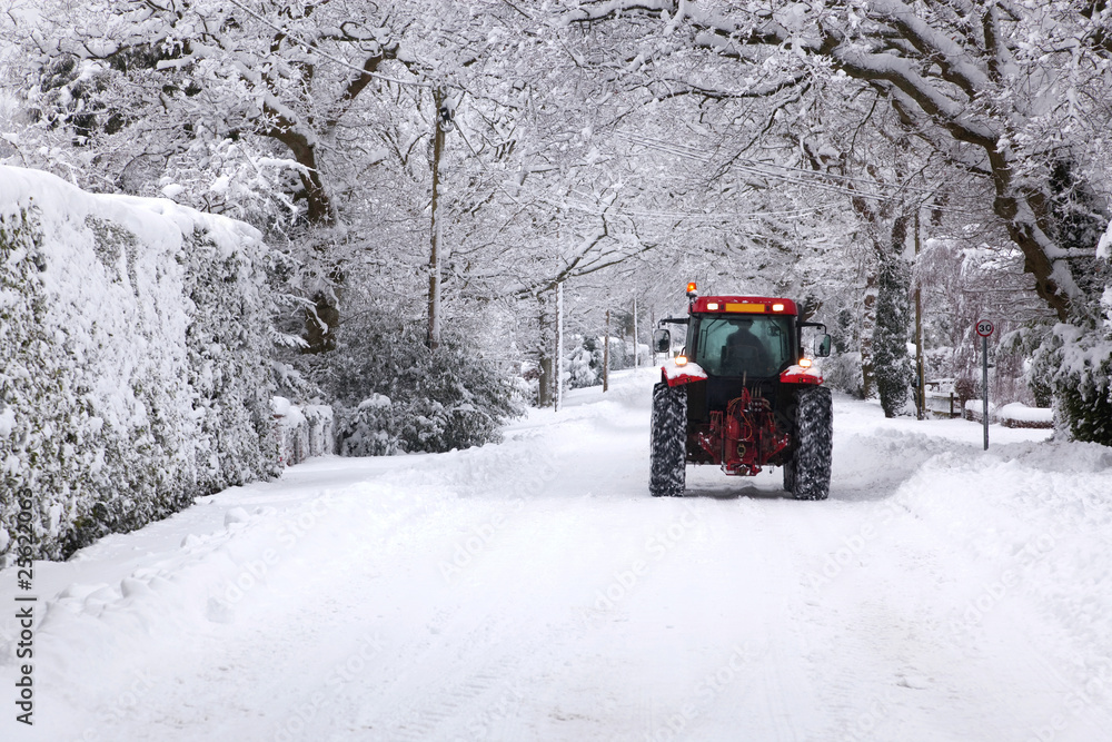 Fototapeta premium Tractor driving down a snow covered road
