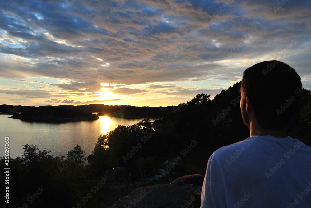 Fototapeta premium young man from behind looking at sunset