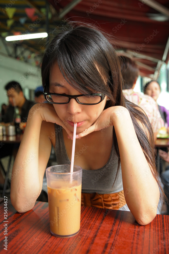 Naklejka premium girl drinking a Hong Kong-style milk tea in Dai pai dong