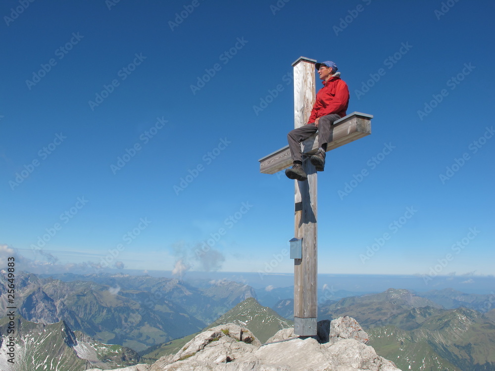 Obraz premium Bergsteiger am Gipfel mit Akrobatik auf Kreuz