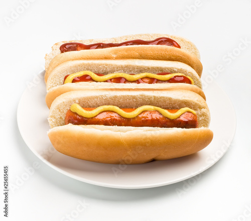 three classic hot dogs with mustard and ketchup on a plate