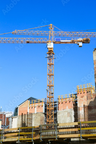 Building crane and building under construction on blue sky