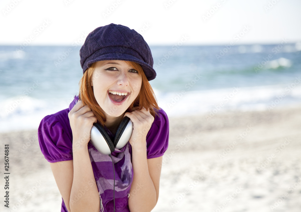 Portrait of red-haired girl with headphone on the beach. Portrait of red-haired girl with headphone on the beach.