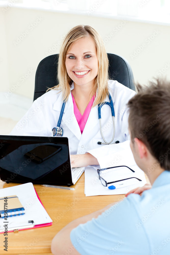 Smiling female doctor using her laptop and talking to her male p Smiling female doctor using her laptop and talking to her male p