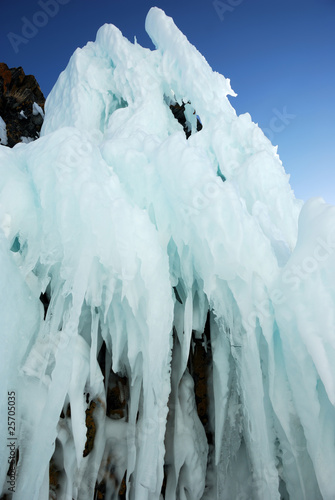Ice-covered cape rocks of the lake shore with icicles