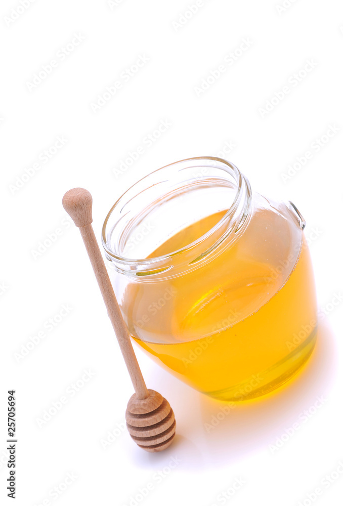 Honey in a glass jar with wooden dipper Honey in a glass jar with wooden dipper