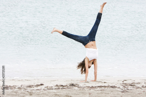 young girl doing gymnastics on beach
