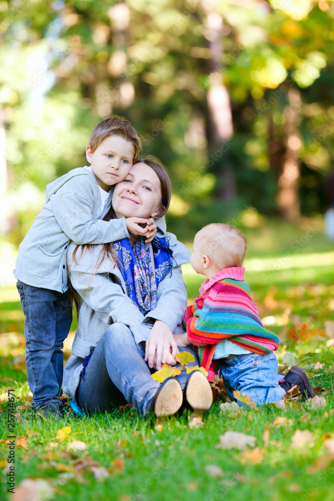Fototapeta premium Mother and two kids sitting on grass
