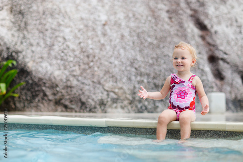 Toddler girl splashing in swimming pool