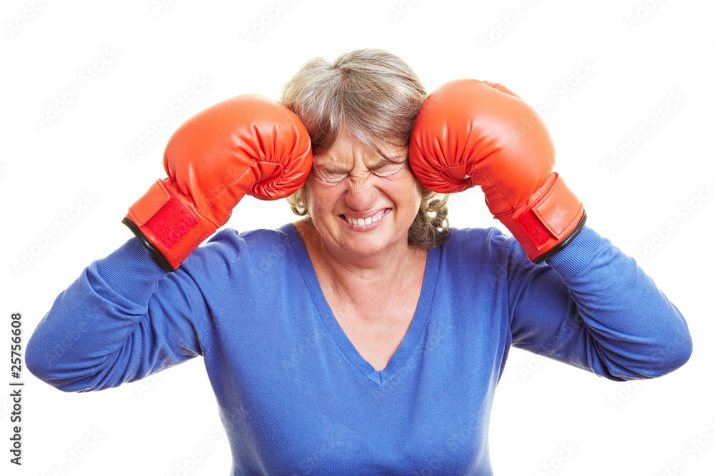 Seniorin drückt Boxhandschuhe an Kopf