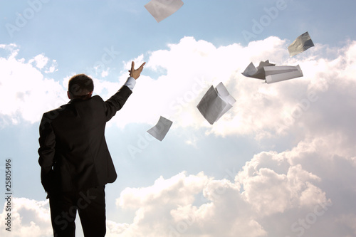 The businessman throws a pile of documents upwards, aside.