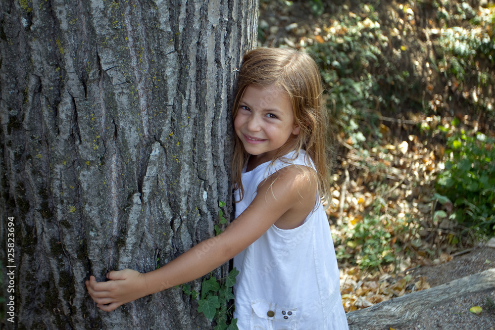 Girl hugging tree trunk and smiling Girl hugging tree trunk and smiling