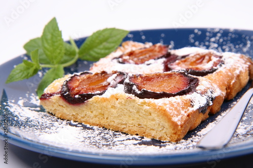 Piece of Plum Pie covered with powder sugar with a mint twig