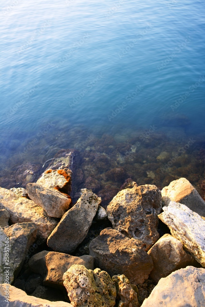 Blue rocky sea shore fading to turquoise dock port stones Blue rocky sea shore fading to turquoise dock port stones