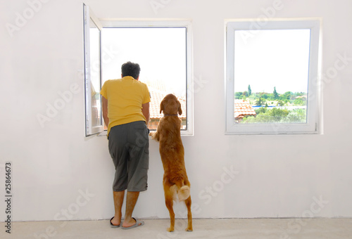 Man and dog looking through window photo