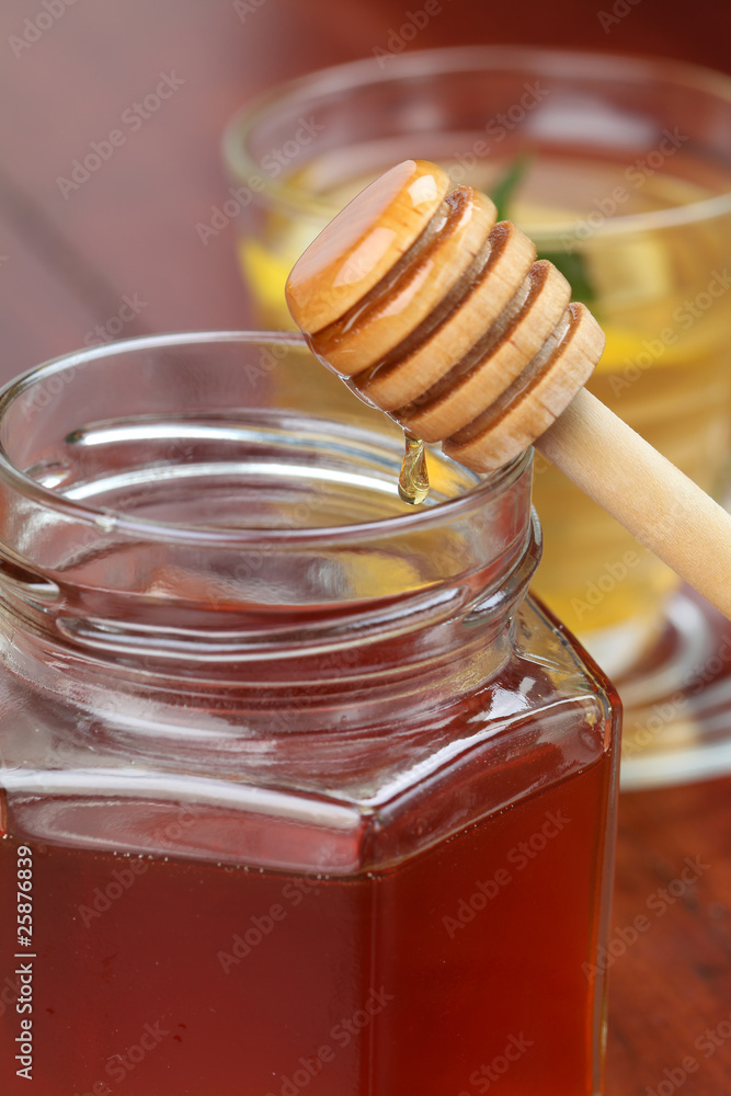 Jar and honey dipper with honey and a cup of tea with lemon Jar and honey dipper with honey and a cup of tea with lemon
