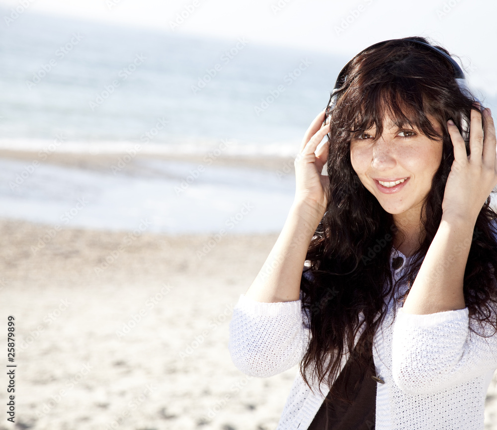 Pretty young woman with headphone on beach