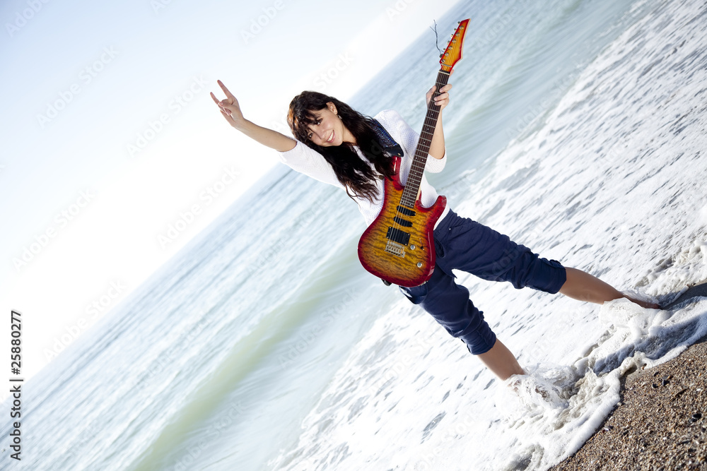Pretty young woman with guitar on beach