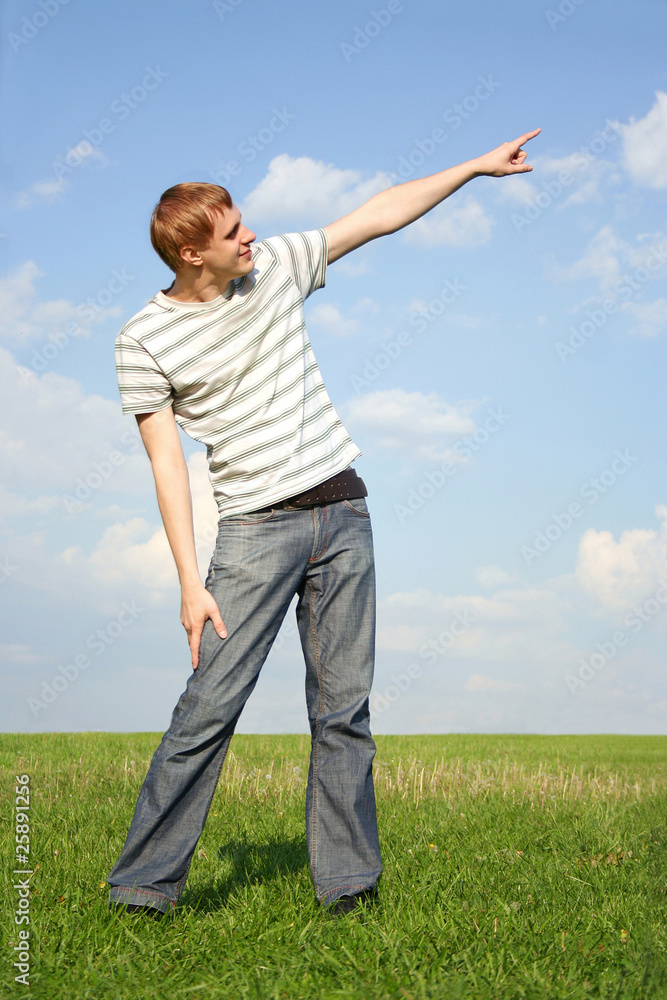 young handsome man standing on summer lawn and pointing for fing