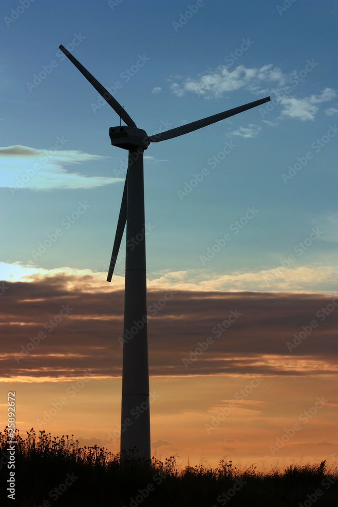 Windmill silhouette against cloudy sunset background Windmill silhouette against cloudy sunset background