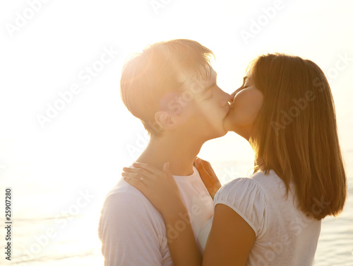 Couple kissing in sunrise at the beach.