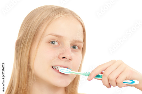 A young woman looks to the camera while brushing her teeth