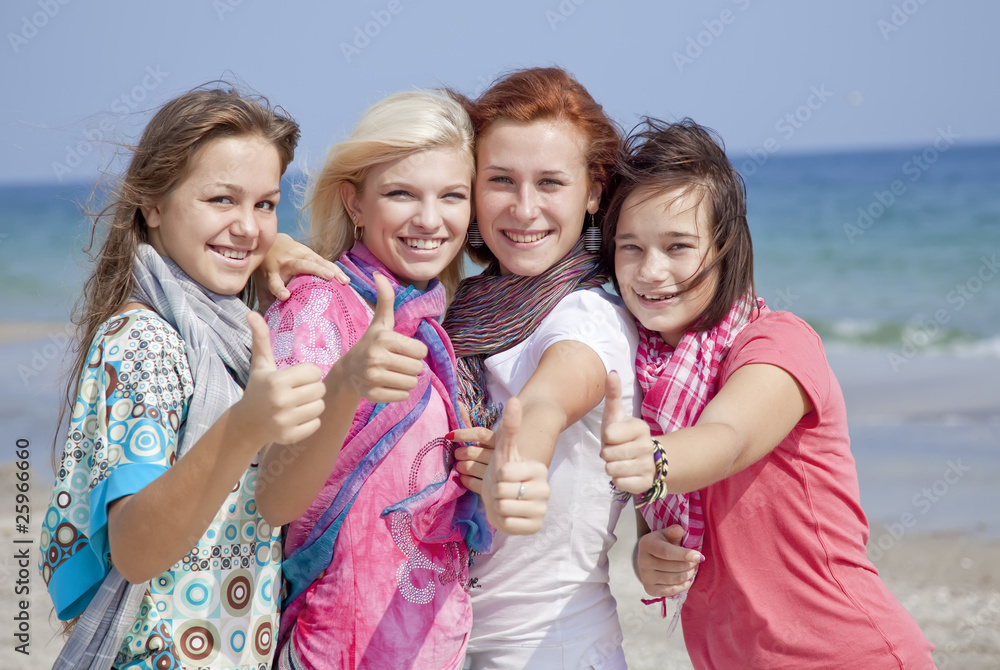 Four hugging girlfriends at the beach show OK symbol. Four hugging girlfriends at the beach show OK symbol.
