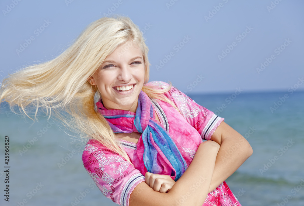 Young blonde girl in pink on the beach.