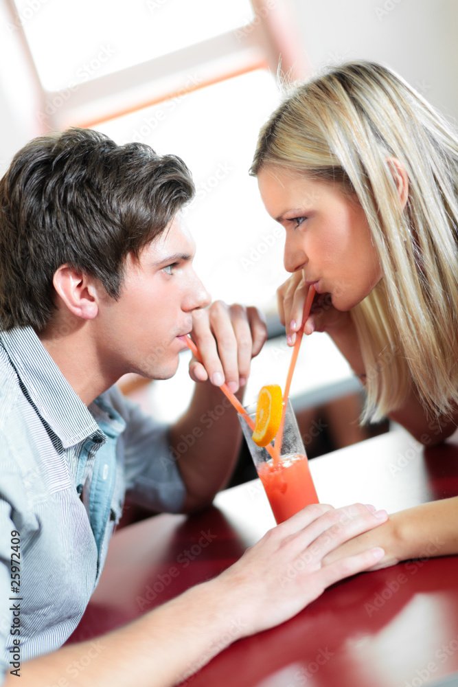 Young couple drinking one coctail with two straws Young couple drinking one coctail with two straws