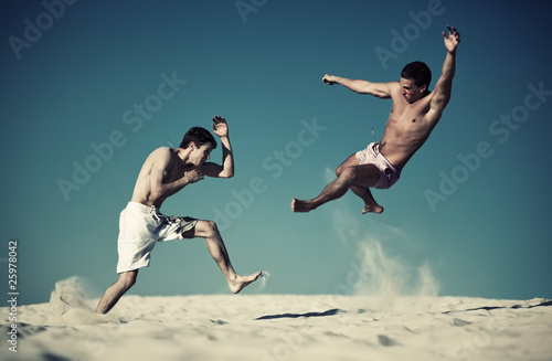 Two young men sport fighting on beach