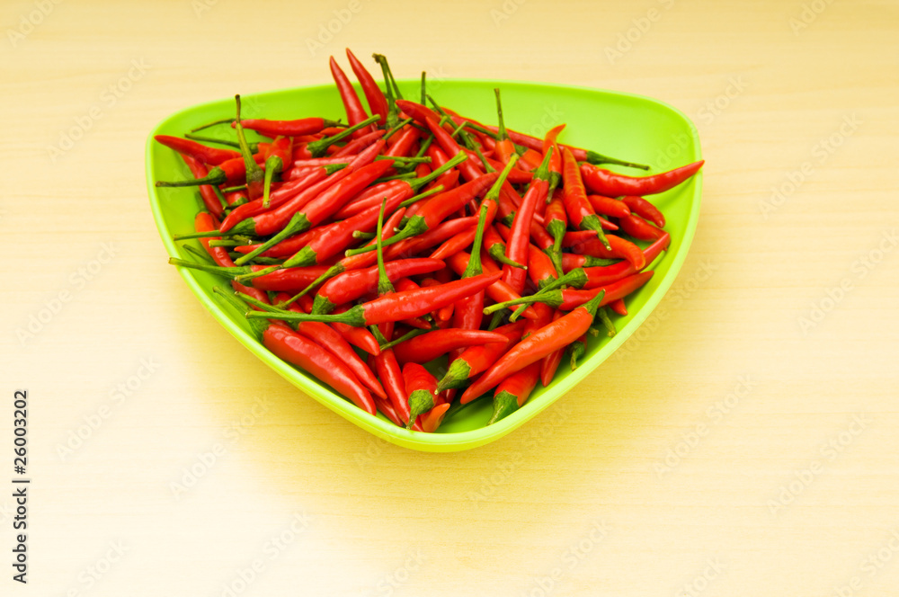 Hot peppers in the plate on wooden table Hot peppers in the plate on wooden table