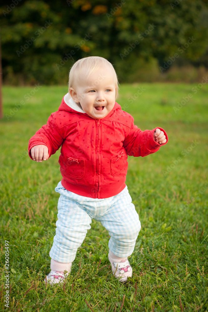 young cheerful baby running on the grass in park young cheerful baby running on the grass in park