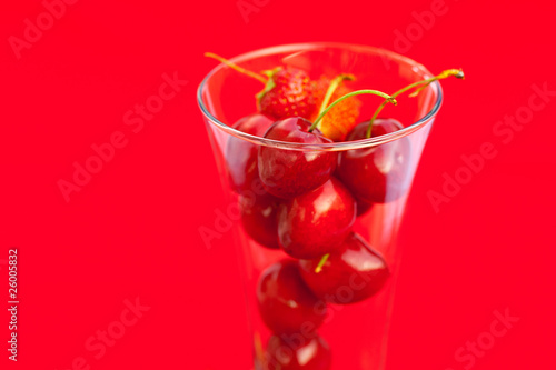 glass of cherry and strawberry on a red background