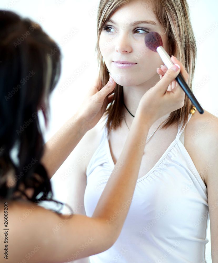 pretty young woman having powder applied by a make-up artist/bea pretty young woman having powder applied by a make-up artist/bea
