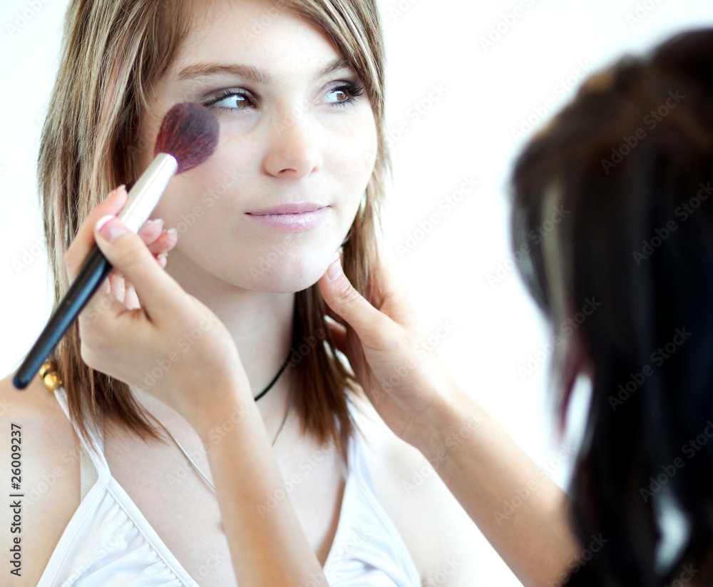 pretty young woman having powder applied by a make-up artist/bea pretty young woman having powder applied by a make-up artist/bea