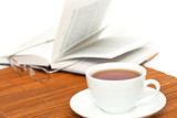 white cup of tea and book with glasses