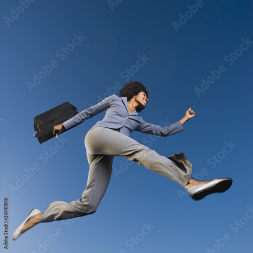 African businesswoman carrying briefcase in mid-air
