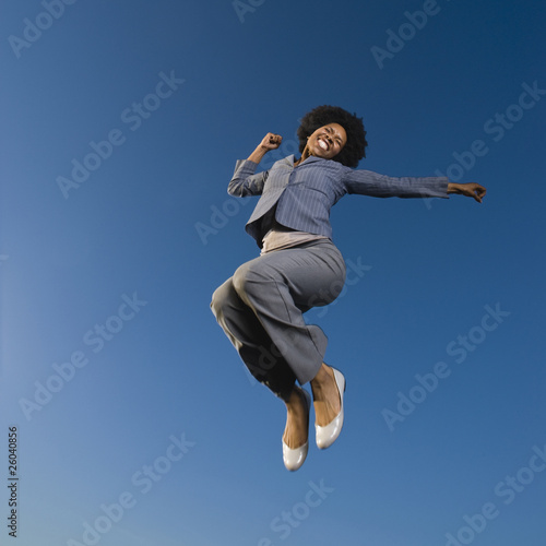African businesswoman jumping in mid-air