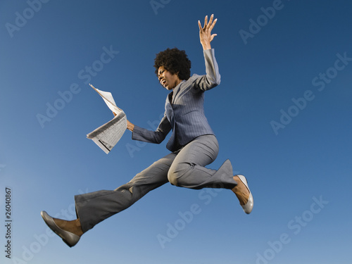 African businesswoman reading newspaper in mid-air