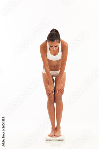 Young woman in underwear on scale weighing herself